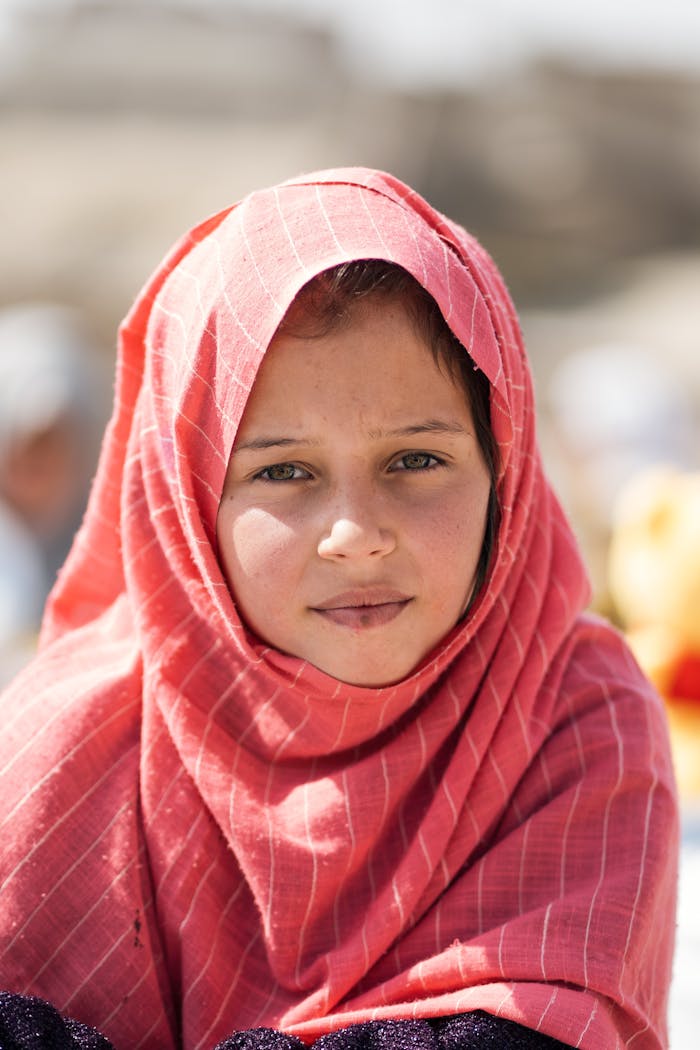 Captivating portrait of an Afghan girl wearing a red hijab, showcasing cultural diversity and resilience.